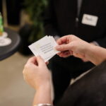 Eine Person hält mehrere Check-in Cards mit Gesprächsfragen in den Händen.